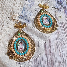 BO Mademoiselle Noellia avec des cabochons ovales repr&eacute;sentant une femme avec un chapeau et un n&oelig;ud blanc &agrave; laquelle s&rsquo;ajoute des cristaux, cha&icirc;nes strass P&ecirc;che et Turquoise sur crochets en plaqu&eacute; Or
