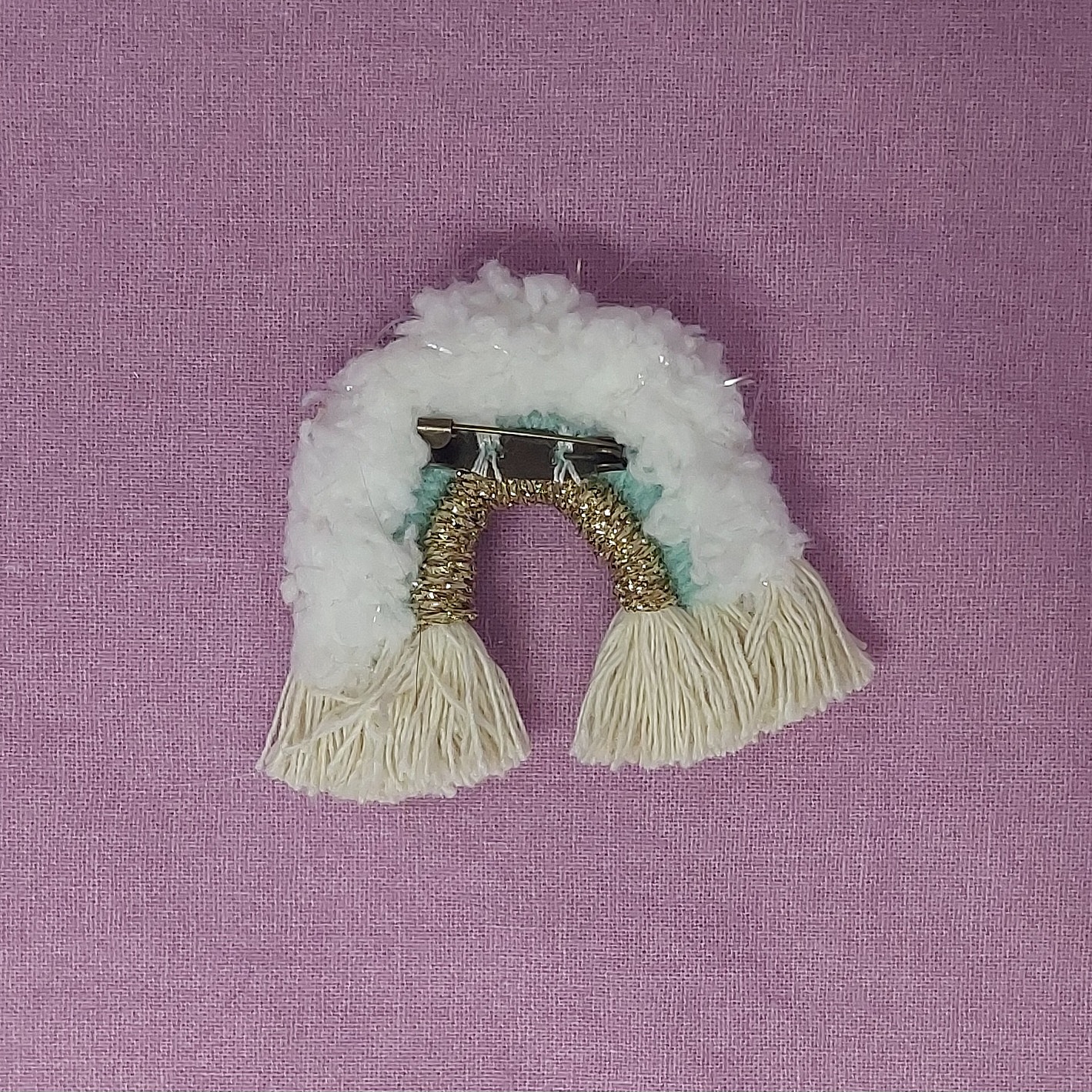 Broche arc-en-ciel en macramé blanc, vert et doré.