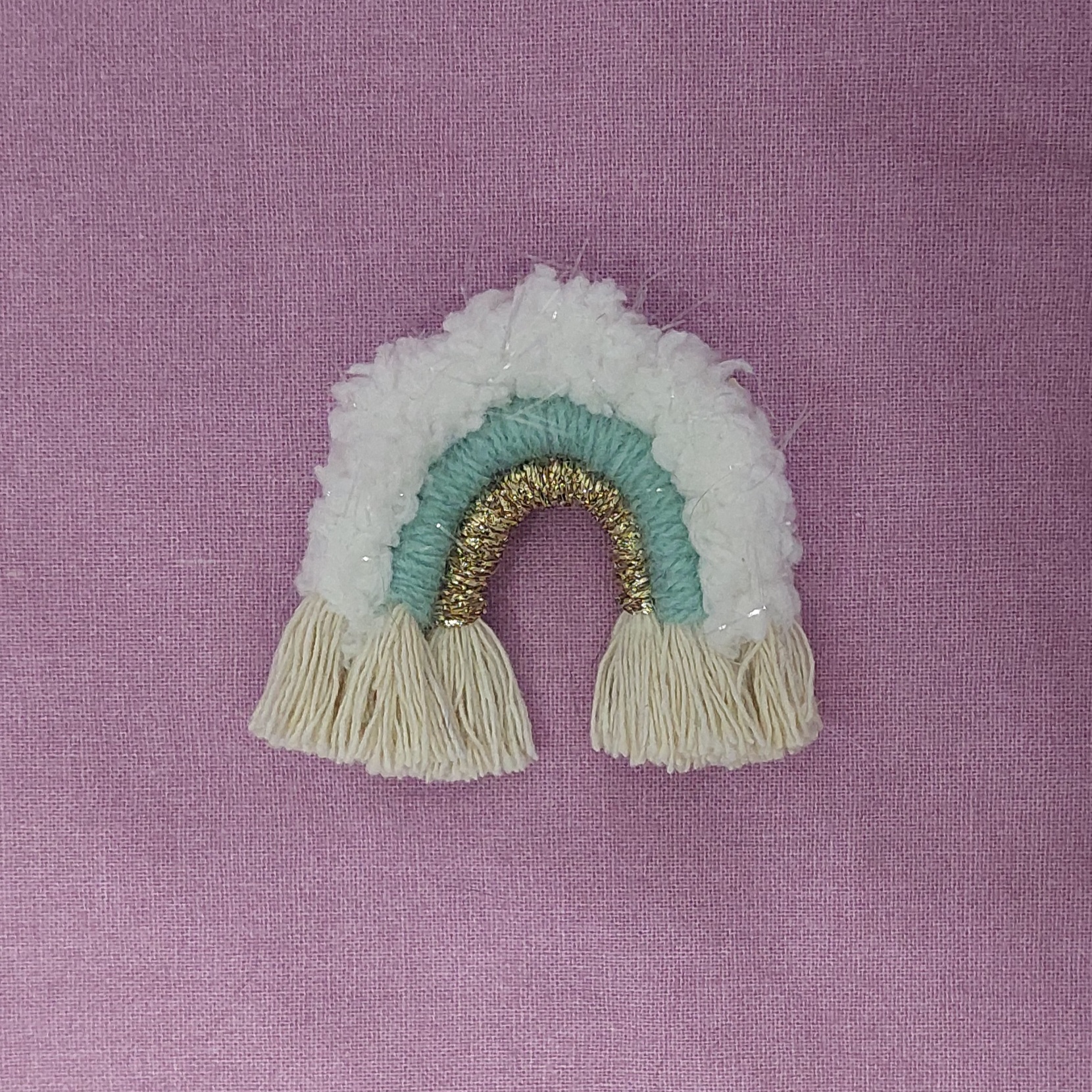 Broche arc-en-ciel en macramé blanc, vert et doré.
