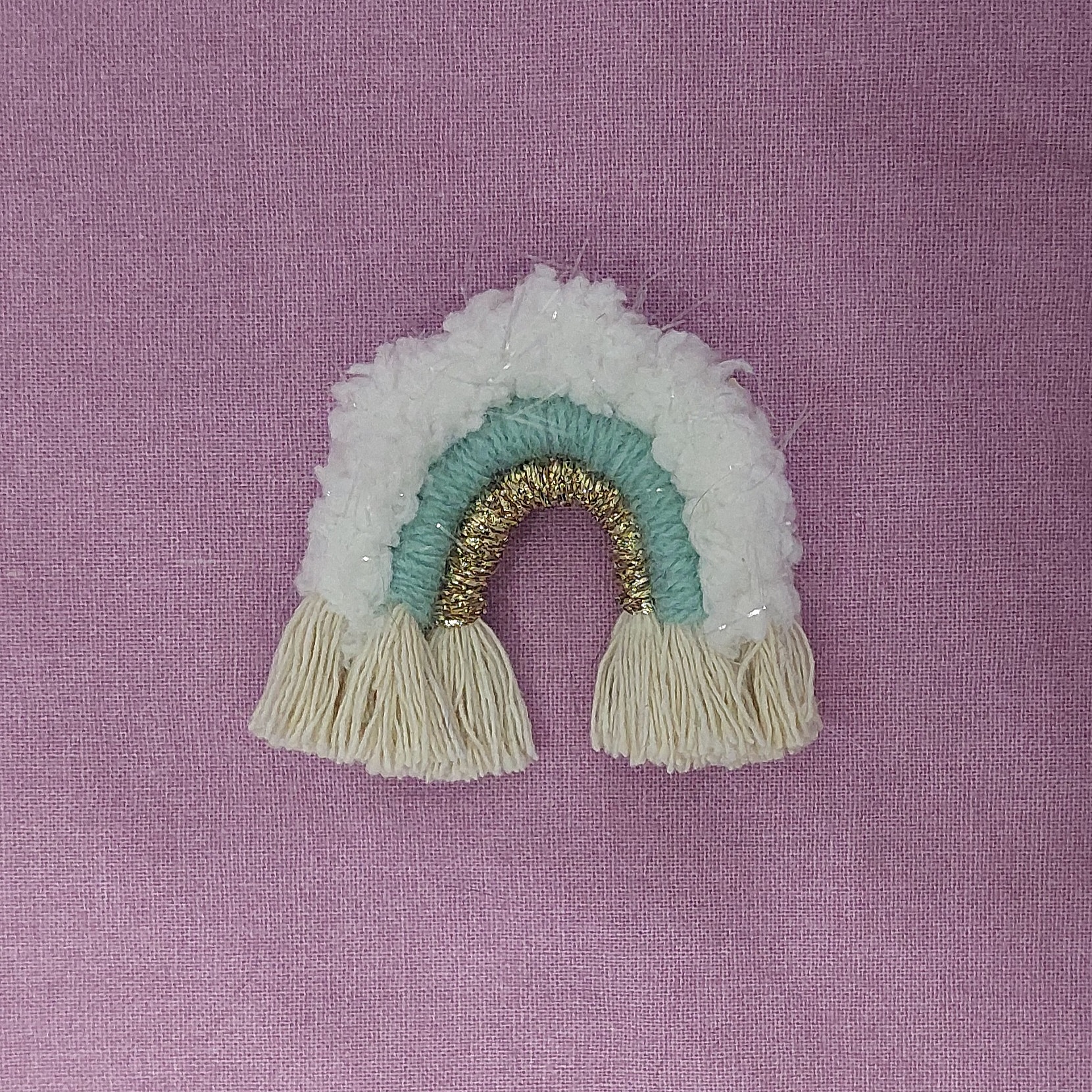 Broche arc-en-ciel en macramé blanc, vert et doré.