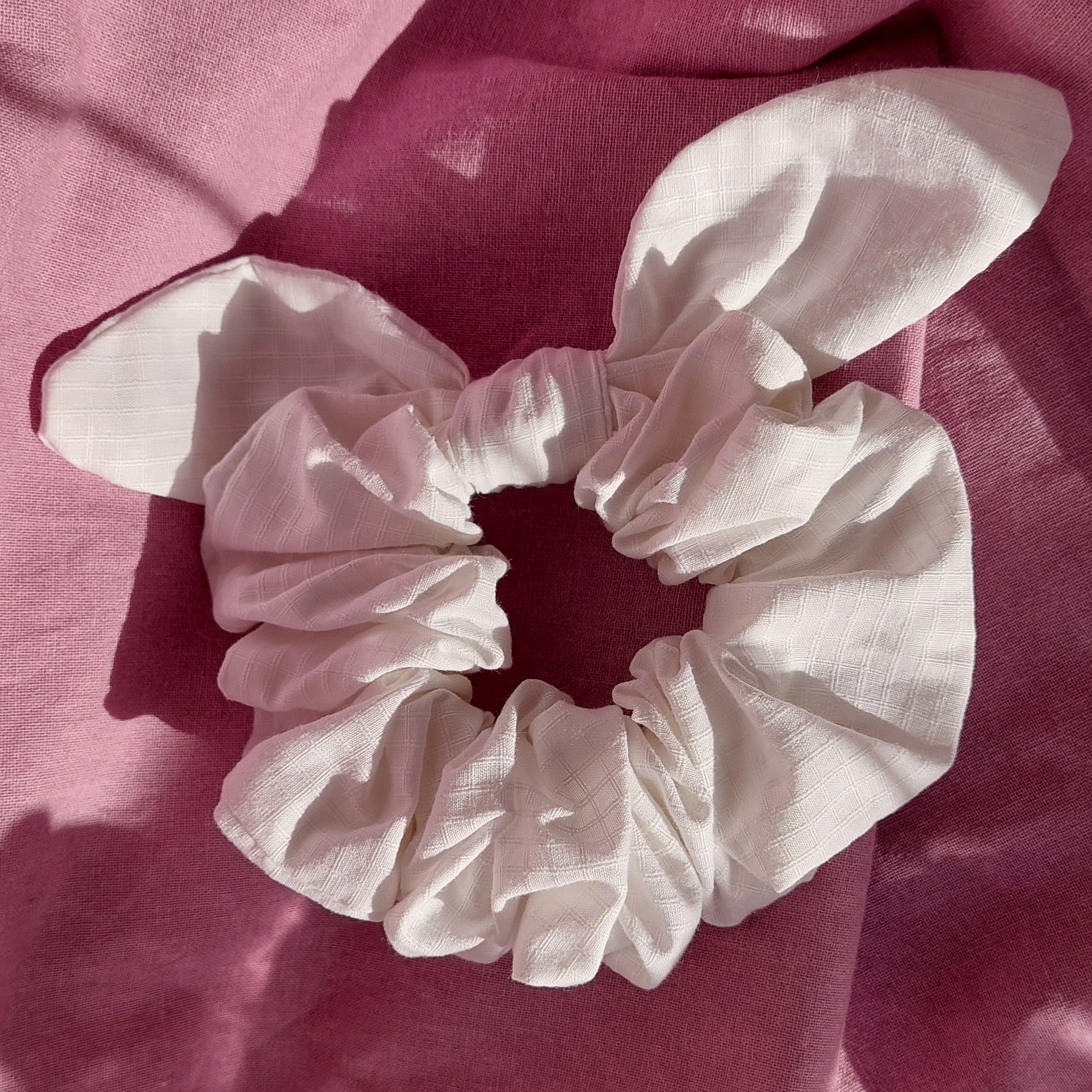 Chouchou foulchie blanc à carreaux sur fond rose.